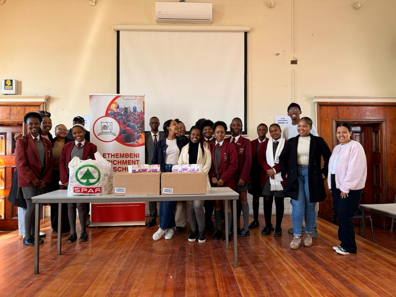 Group standing with donated sanitary products at a school outreach